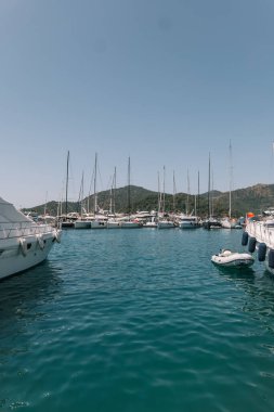 Gocek - Fethiye, Türkiye - 10 Mayıs 2025: Bereketli tepeler ve açık mavi sularla çevrili sakin bir körfezde dinlenen yelkenliler.