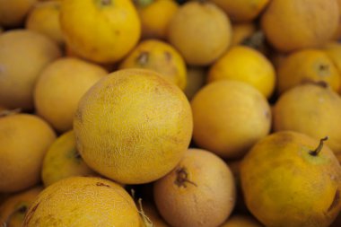 Taze sarı karpuzlar bir araya toplanmış, canlı renklerini sergiliyorlar öğleden sonra hareketli bir pazarda.