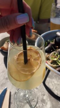 Turunçgil dilimli canlı bir içecek güneşli bir açık hava masasında deniz ürünleri yemeğinin tadını çıkardı..