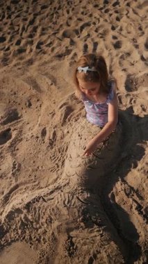 Bir çocuk sıcak öğleden sonra güneşinin altında kumları yaratıcı bir heykele dönüştürüyor..