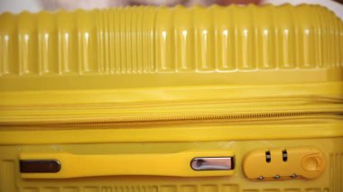 Canlı sarı bir bavul göze çarpıyor, renkli bir ortamda seyahat ve maceraya hazır..