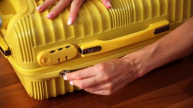 Bir kişi, bir yolculuğa hazırlanırken parlak sarı bir bavula eşyalarını yerleştirir..