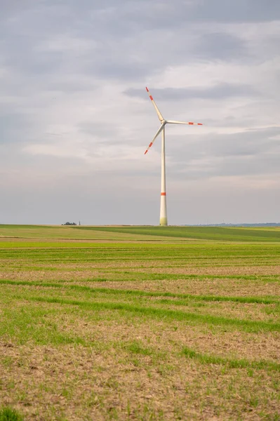 Wind turbine with agricultural field in front during cloudy day, mainz, germany, vertical shot