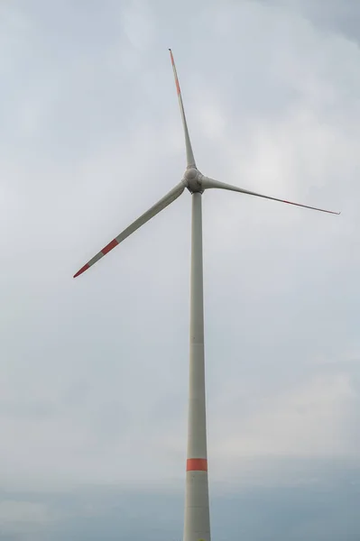 Modern wind turbine renewable energy during daylight with cloudy sky, view from low angle, vertical shot