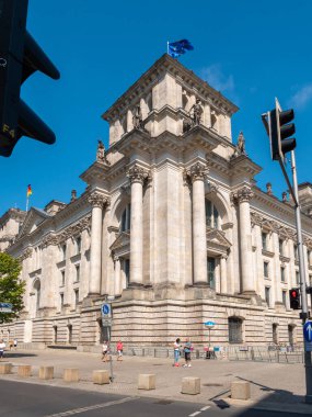Bundestag Berlin Building, side view with traffic lights and people walking in front, long exposure, during summer with clear sky, vertical shot