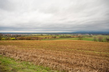 Cityscape of Schaafheim and village next to it, with agricultural fields in the front and Mountain range in the background during cloudy day, Germany
