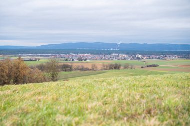 Cityscape of Schaafheim, with agricultural fields in the front and Mountain range in the background during cloudy day, Germany