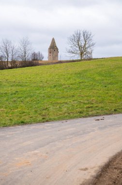 Wartturm, Schaafheim on a hill with agricultural path and meadow in front during cloudy day, vertical shot