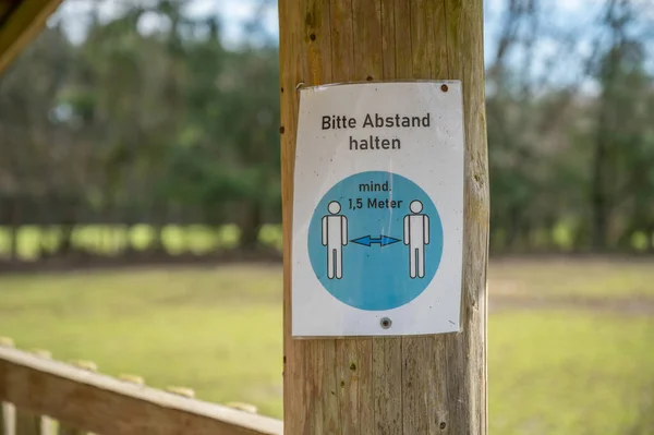 Keep distance of 1,5 meters german Corona Covid-19 Rule Sign on a tree trunk at a amusement park safari park