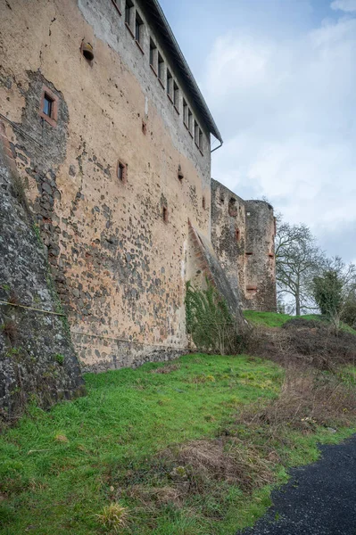 Old Castle walls with windows on top at the side of Ronneburg Castle, during cloudy day, Germany, vertical shot