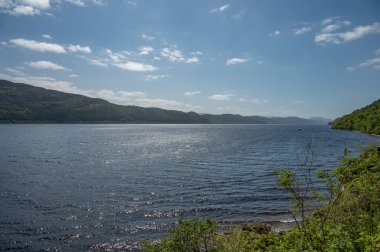 İskoçya 'daki Loch Ness Gölü' nün önü ağaçlarla dolu açık gökyüzü manzarası