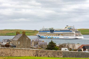 AIDA Bella, Shetland Adaları 'nda bulutlu bir günde, köyün önündeyken uzaktan görüş.