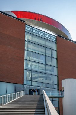 Aarhus 'taki ARoS sanat müzesi, alçak açı, renkli bir tünelden geçen insanlar, önünde merdivenlerle dikey çekim yapan insanlar.