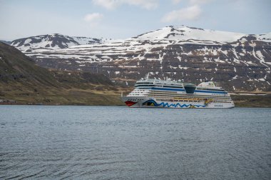 Seydisfjordur, İzlanda fiyordunda bulunan AIDA Bella Cruise Gemisi, arka planda karlı dağ aralığı ile yan görünüm