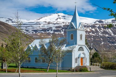 Seydisfjordur, İzlanda 'daki mavi ahşap kilise. Arka planda karlı dağlar var.