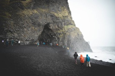 Kara Kum Sahili Reynisfjara 'da arka planda birçok turist var, İzlanda