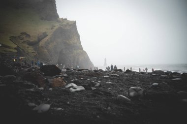 Kara Kum Kumsalı Reynisfjara, uzak mesafede turist, sisli hava, alçak açı, önü taşlı, İzlanda