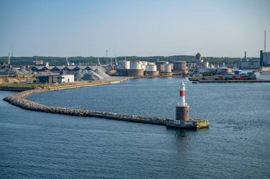 Danimarka 'nın Aarhus Limanı yakınlarında sanayi binaları ve kum dağları olan deniz feneri.