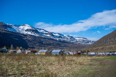 Seydisfjordur, İzlanda 'nın şehir manzarası, harika hava koşullarında bir kar dağının önündeki renkli evler.