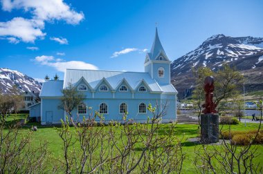 Seydisfjordur, İzlanda 'daki mavi ahşap kilise. Arka planda karlı dağlar var.