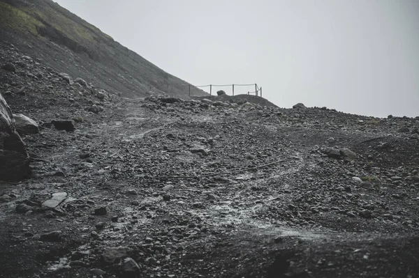 Solheimajokull Buzulu yakınlarındaki gri kayalık arazi yağmurlu havada, İzlanda