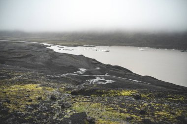 Solheimajokull Buzulu 'nun önündeki güzel manzara yağmurlu havalarda, suda buz parçalarıyla, İzlanda