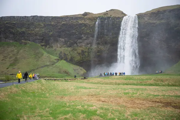 セルジャランズフォスウォーターフォール 雨天の前の雨のカバーで観光客 アイスランド — ストック写真