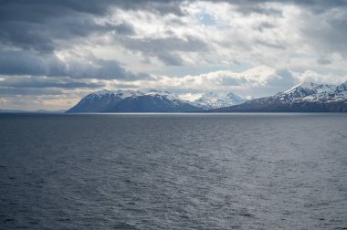 Önünde deniz olan İzlanda karlı dağları bulutlu havalarda, uzaktan görüş, geniş açı görüntüsü