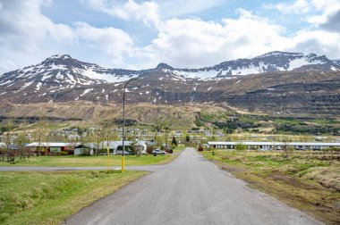 Seydisfjordur, İzlanda 'da ikamet alanı. Önünde binalar, önünde sokaklar ve arkasında karlı dağ sıraları var.