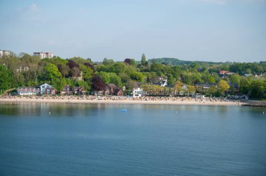 Almanya, Kiel yakınlarında plaj sandalyeleri olan güzel bir sahil. Önünde deniz, uzaktan hava manzarası var.