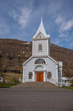 Seydisfjordur 'daki mavi ahşap kilise, ön manzara, alçak açı, cadde önde, dağ arkada, İzlanda