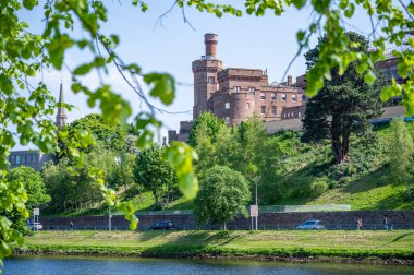 Önünde ağaç yaprakları ve nehir olan Inverness Şatosu, İskoçya