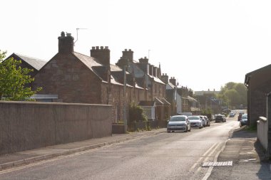 Gün doğarken Invergordon 'da konut binaları olan yerleşim yerleri, İskoçya caddesinde park etmiş arabalar.