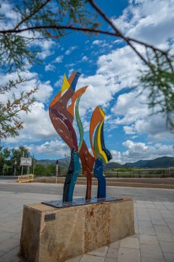 Andratx Limanı 'ndaki renkli heykel, Mallorca, önünde bir ağacın dalları, dikey çekim, Mayorka