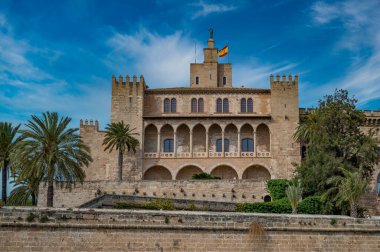Palma de Mallorca 'daki La Almudaina Kraliyet Sarayı' nda büyük hava koşullarında önlerinde ağaçlar, uzaklardan Mayorka manzarası.