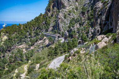 Serra de Tramuntana, Mallorca 'da tüneli olan dağ yolu, uzaktan görüş, arka planda deniz, Mayorka
