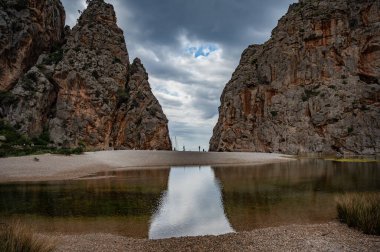 Sa Calobra, Mallorca plajı bulutlu havada kayalık dağ duvarları arasında, göl önünde, geniş açılı çekim, Mayorka