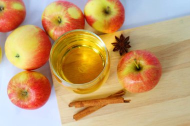 Bir bardak elma suyu ve ahşap arka planda taze elma tarçın ve yıldız anason..