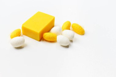 Beyaz arka planda beyaz ve sarı kozalı sarı el yapımı sabun..