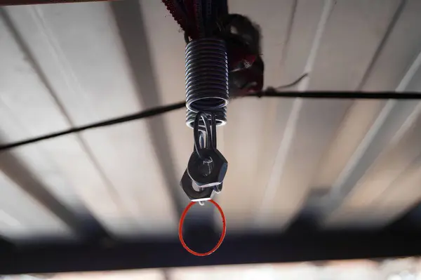 Close-Up View of a Metal Spring and Clip Attached to a Wire Indoors