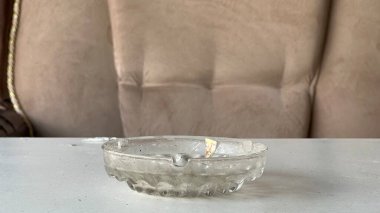 Temiz cam bir kül tablası yumuşak, bej bir kanepenin yanındaki masada duruyor..