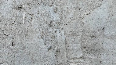 Kaba bir doku ve ince desenlere sahip beton bir duvarın yakın görüntüsü.