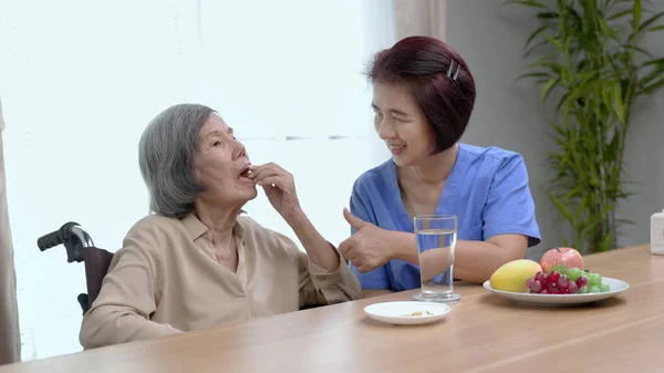 在养老院为老年妇女提供鱼油的护理人员 — 图库照片
