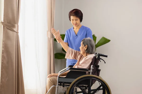 Äldre Asiatisk Kvinna Som Stretchar Rullstol Vardagsrummet Med Sjukgymnast — Stockfoto