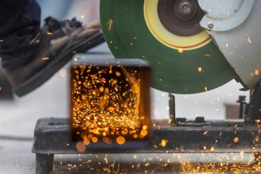 Worker  cutting steel square pipe in constuction site.