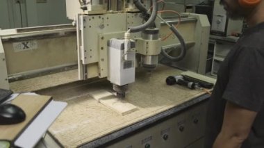 Üst düzey adam CNC makinesini fabrikadaki ahşap ürünleri kesmek için kullanıyor..