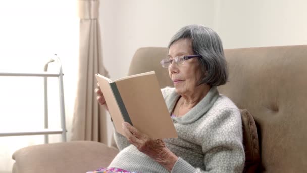 Asyalı Yaşlı Kadın Huzurevinde Rahatlamak Için Kitap Okuyor — Stok video
