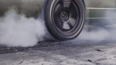 Yarış pistinde kalkış çizgisinde yarış arabasının lastiği yanıyor.