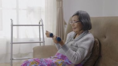 Elderly woman is exercise on sofa at nursing home.
