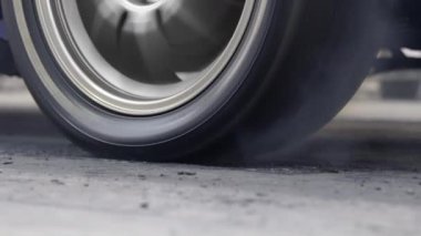 Yarış pistinde kalkış çizgisinde yarış arabasının lastiği yanıyor.